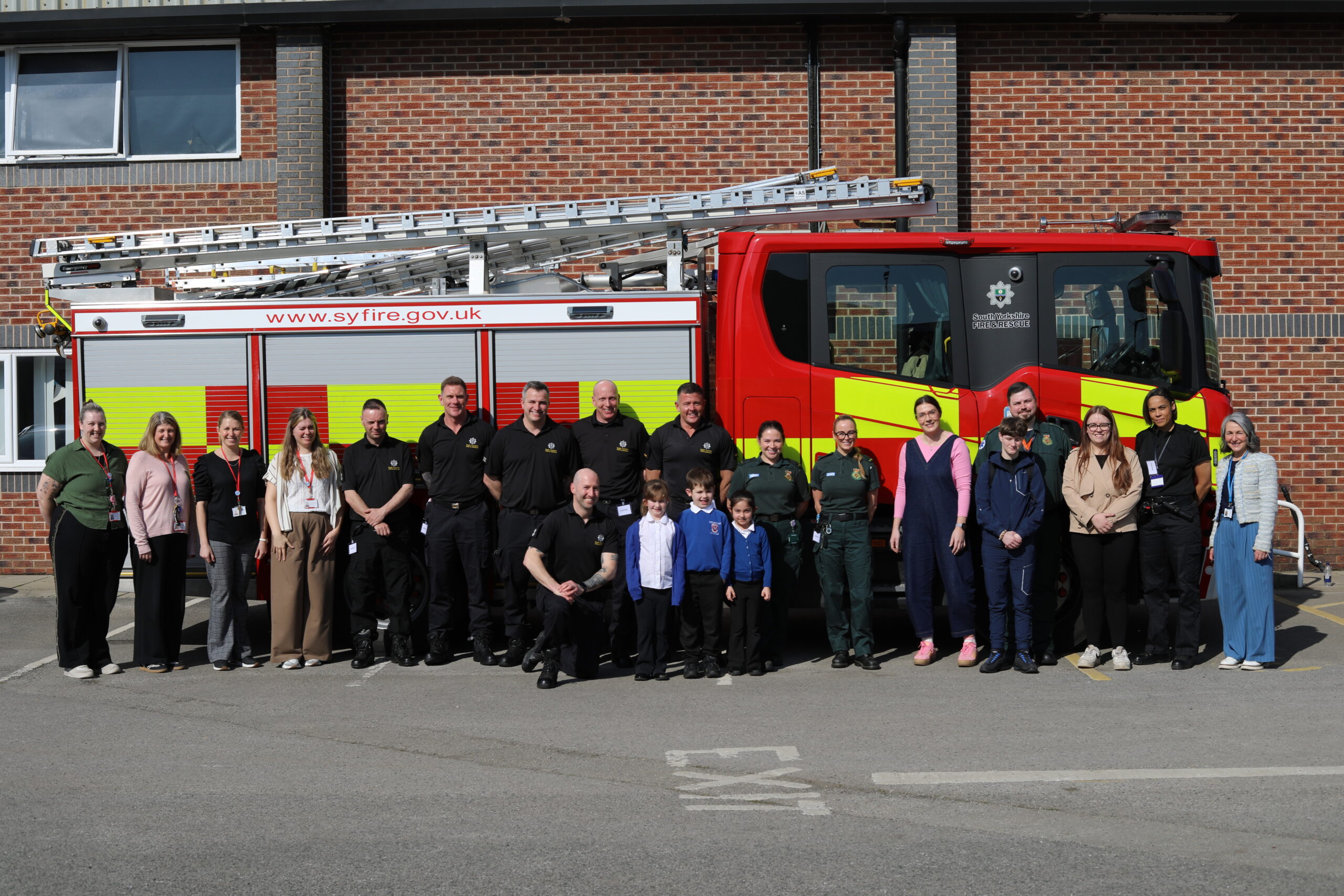 Members of the emergency services stood along the side of a fire engine with pupils, staff and students from The Carr Fenton Foundation